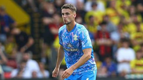 Taylor Harwood-Bellis playing for Southampton against Watford in their blue and pink away strip.
