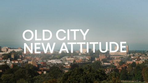 The Norwich skyline in the bottom half of the image, with a blue sky in the top half. The text is across the middle, saying 'old city, new attitude'.