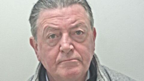 Patrick Coyle is clean-shaven, with swept back greying hair.