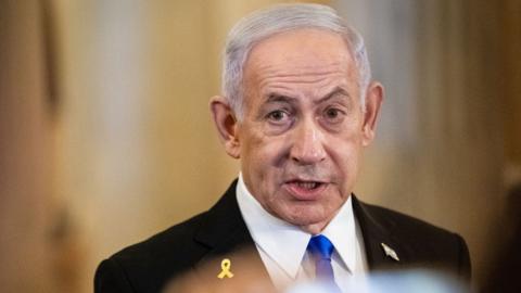 Israeli PM Benjamin Netanyahu looks at the camera while speaking at Capitol Hill in Washington DC on 8 July, while wearing suit and tie.