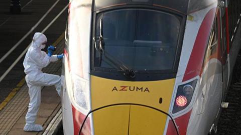 Forensic police officers examine the LNER train as it sits in Huntingdon Station