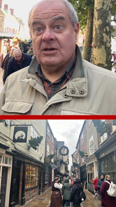 Man in top half of the screen with a grey jack on. York Shambles with people walking along the street is in the bottom half of the screen.