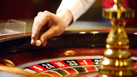 Photograph of a ball about to be dropped onto a roulette wheel