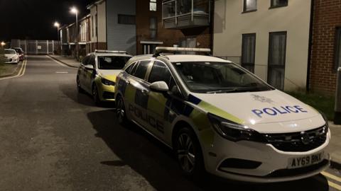 Two police cars parked up at night outside a block of flats