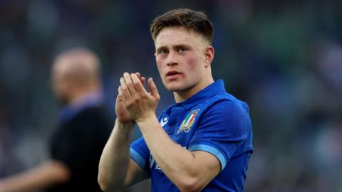 Stephen Varney wearing an Italian rugby shirt, and applauding fans.