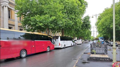 A row of coaches can be seen parked on the left hand side of St Giles in Oxford, looking from the centre of Oxford towards Woodstock Road.


