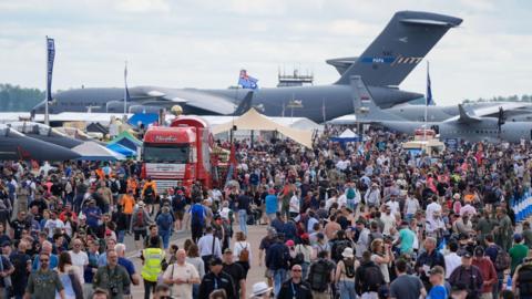 A photo of this year's Royal International Air Tattoo, showing a huge crowd of people walking around the grounds as large aircraft loom behind them