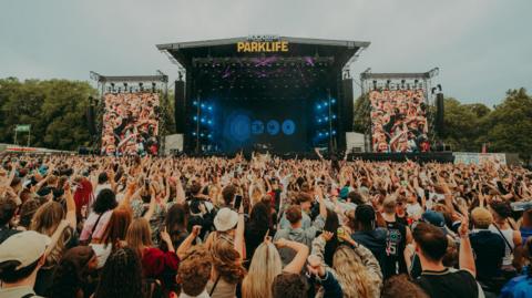 Music fans with their hands in the air in front of a stage at Parklife at this year's festival