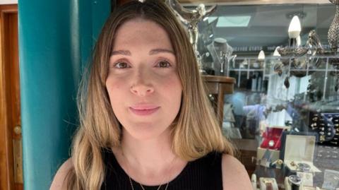 Farah Ozlati with long blond hair standing in a jeweller's shop