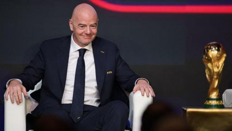 Gianni Infantino sat in a chair next to the World Cup trophy.