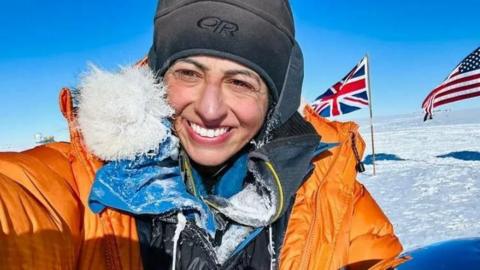 Chandi in a hat and a big orange coat in the South Pole.
