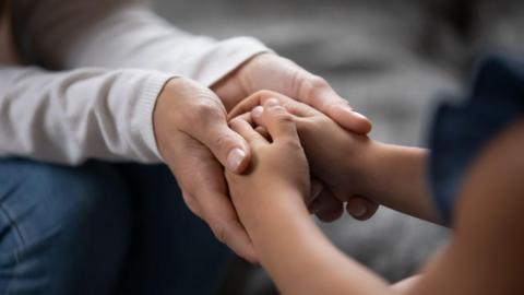 adult holding child's hands