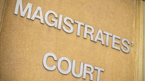 A close up of a sign that says magistrates' court in metallic capital letters on a concrete backdrop. 