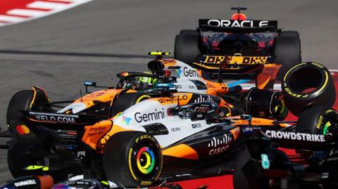 A wheel flies off the McLaren of Lando Norris after he collided with team-mate Oscar Piastri at the start of the United States Grand Prix sprint race