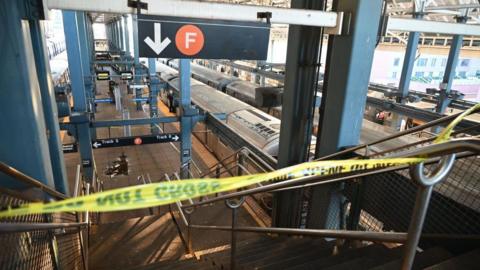 Caution tape closes off a subway platform under a sign directing people to F line trains.