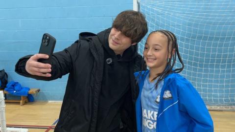 A man taking a selfie-style photo with a smiling player.