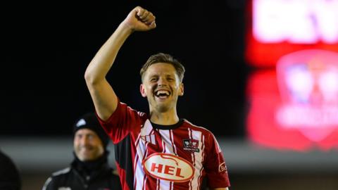 Exeter City defender Jack Fitzwater with arm in air smiling and celebrating