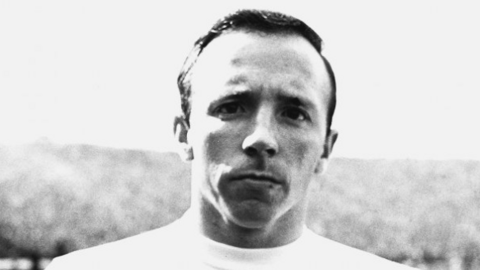Image is a black and white photo of Nobby Stiles, in an England shirt, during his playing career