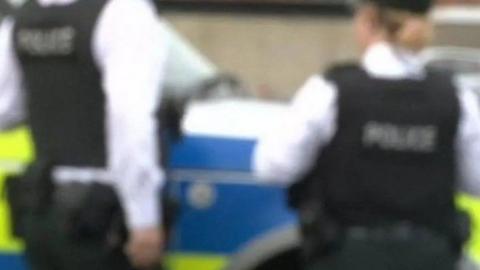 Two police officers blurred standing in front of a police vehicle 