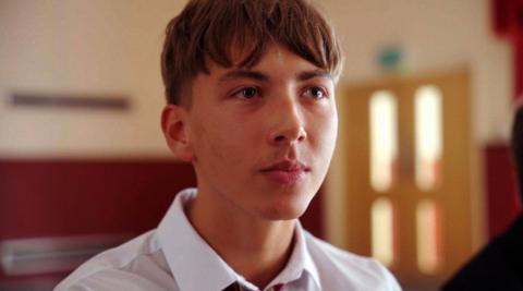 A screenshot of Dexter Henson in the short film. He has short brown hair and is looking at someone