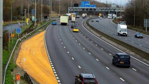 An image if the M1 near Luton which shows a completed emergency area at the side of the four-lane motorway. It is on the left-hand side of the image and is 100 metres long and bright yellow in colour.