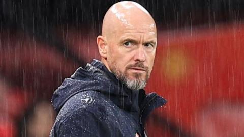 Manchester United manager Erik ten Hag stands on the touchline in the rain at Old Trafford