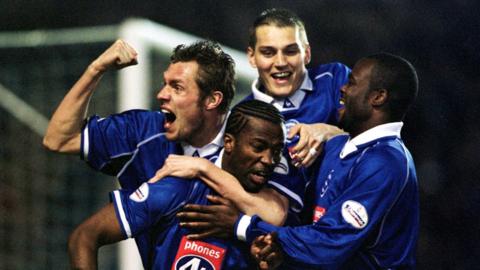Four Birmingham City players celebrate ferociously hugging each other, pumping fists and shouting