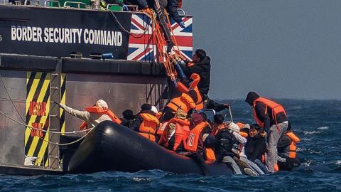 Men climbing from a small boat to a big one