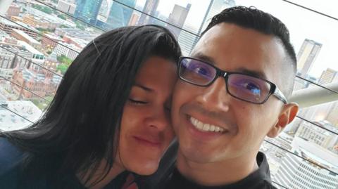 Retired Staff Sergeant Wilmer Trujillo and his wife, Arelys Barahona Martinez, in an undated photo. It is a selfie photo; Arelys smiles with her eyes closed as she leans into Sgt Trujillo, who is looking at the camera and smiling.