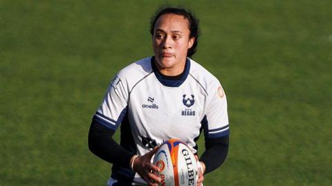 Ruahei Demant holding a ball between both her hands while standing on the pitch during a match for Bristol Bears