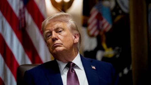 Donald Trump dressed in blue suit looking at camera with a serious look on his face