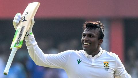 Senuran Muthusamy raises his bat after scoring a century for South Africa