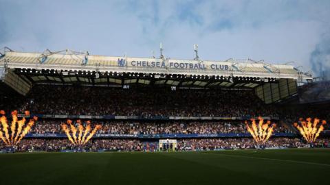 Stamford Bridge stadium in the sun with fireworks going off as the teams walk out on to the pitch