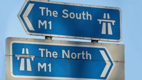 Two motorway signs, one pointing South, one pointing North