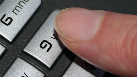 A finger presses the number nine button on a landline telephone