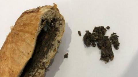 Beef Wellington cut open with filling exposed on left of image and some of the filling out on the right