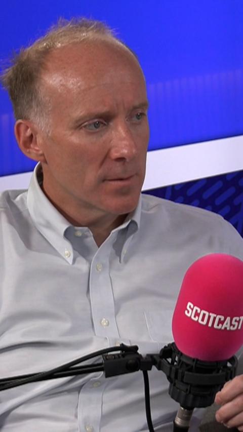 Man in white shirt in radio studio with blue background.