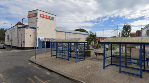 A road with a number of bus stops, behind is a Mecca bingo premises 