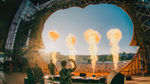 DJ on stage with crowds in front 