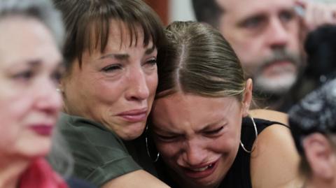 Dylan Mortensen gets a hug after speaking at the sentencing hearing of Bryan Kohberger after he was convicted - she looks extremely distressed and is having her head held