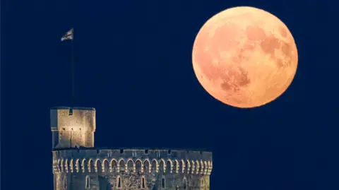 A large moon shining in a clear sky over Windsor Castle