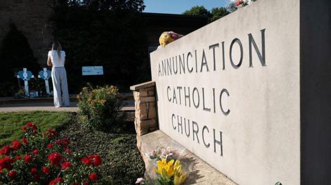 A memorial to yesterday's shooting victims sits in front of Annunciation Catholic Church