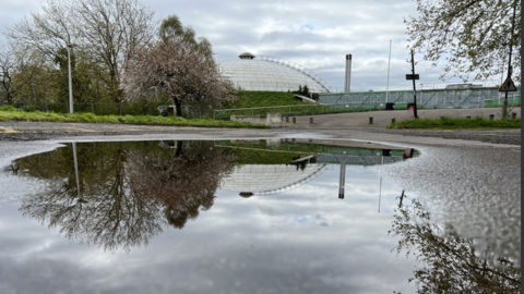 Oasis dome reflected in waterlogged car park