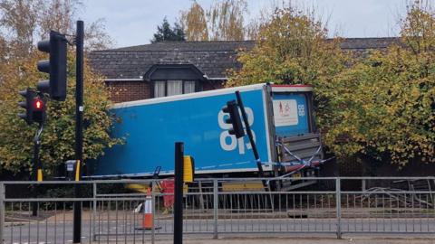 A blue lorry has come off the road and hit a wall.