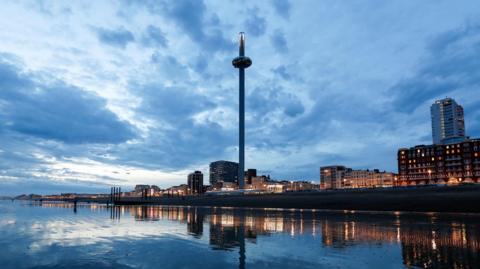 A large tower on the front of an city coast line at night. 