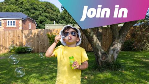 Boy blowing bubbles in a garden