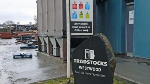 A stone block being used as a sign for Tadstocks sits at the door of an inudstrial unit