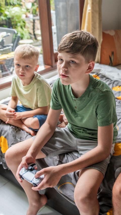 Two boys play video games in their bedroom