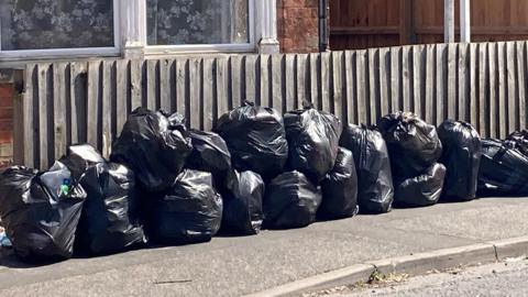 A row of black bin bags on a street in Spalding