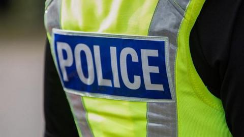 A police officer wearing a hi-vis jacket that says the words "Police" on the back